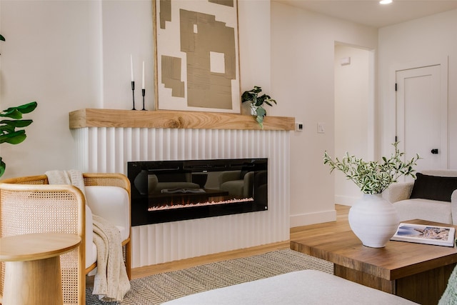 living room with recessed lighting, baseboards, wood finished floors, and a glass covered fireplace