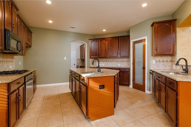 kitchen featuring a sink, visible vents, light stone countertops, and black appliances