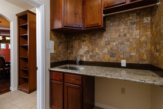 kitchen with tasteful backsplash, light stone countertops, light tile patterned floors, arched walkways, and a sink