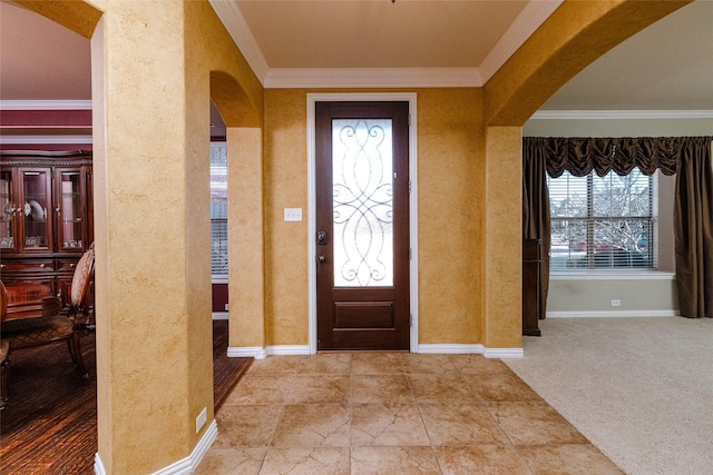 carpeted foyer entrance featuring baseboards, arched walkways, and crown molding