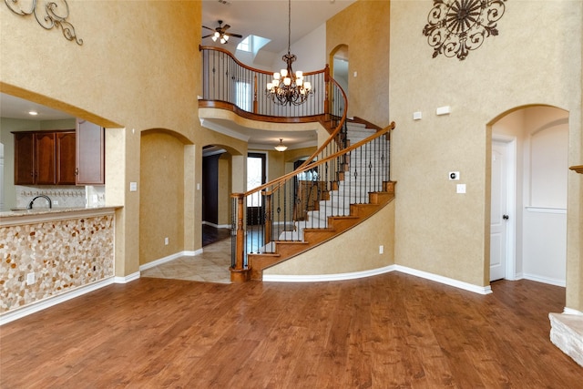 interior space with stairway, ceiling fan with notable chandelier, a high ceiling, and wood finished floors