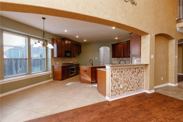 kitchen with light tile patterned floors, tasteful backsplash, arched walkways, and black microwave