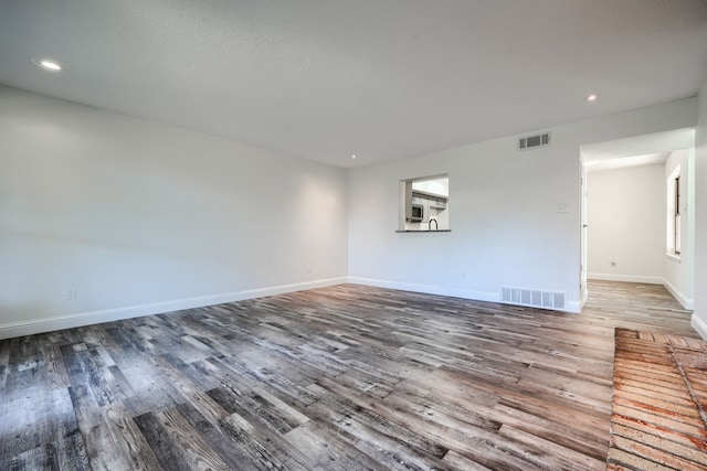 spare room featuring visible vents, baseboards, and wood finished floors