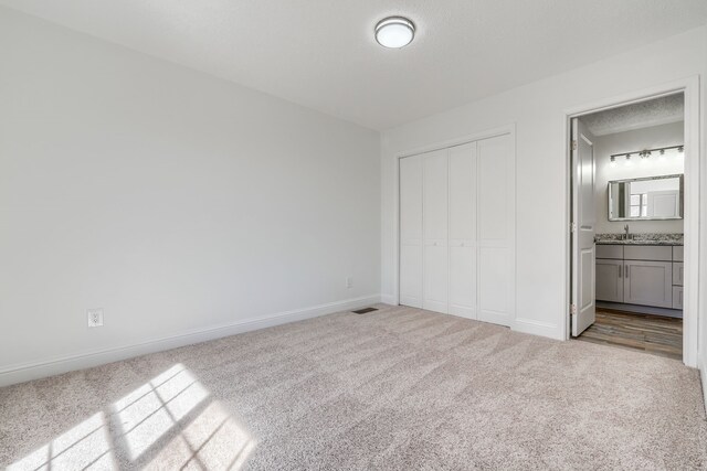 carpeted spare room with visible vents, a textured ceiling, and baseboards