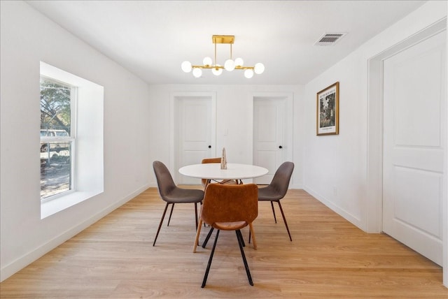 dining space with baseboards, an inviting chandelier, visible vents, and light wood-style floors