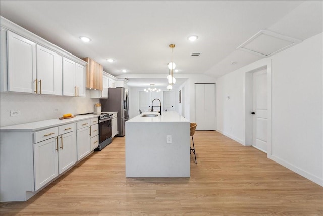 kitchen featuring pendant lighting, a center island with sink, appliances with stainless steel finishes, a sink, and light wood-type flooring