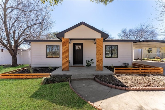 view of front of home featuring a carport, a front yard, fence, and driveway