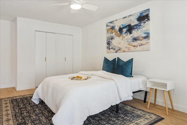 bedroom with a closet, wood finished floors, a ceiling fan, and baseboards