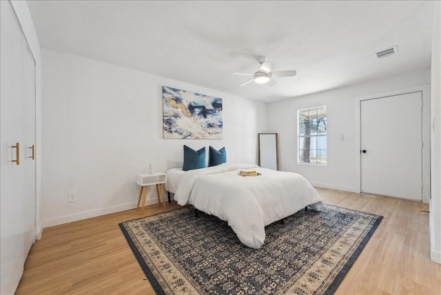 bedroom with light wood-style flooring, visible vents, ceiling fan, and baseboards