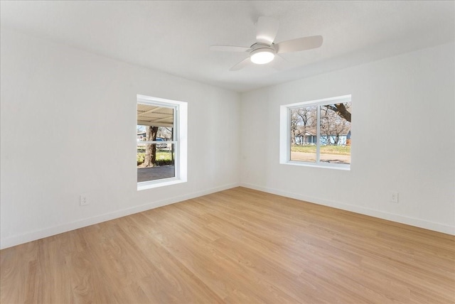 spare room with baseboards, ceiling fan, and light wood-style floors