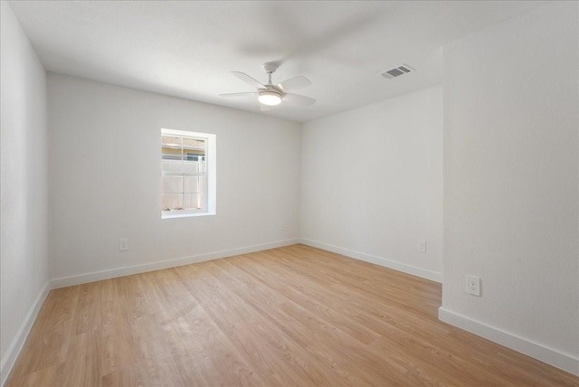 empty room featuring light wood-style floors, visible vents, baseboards, and a ceiling fan