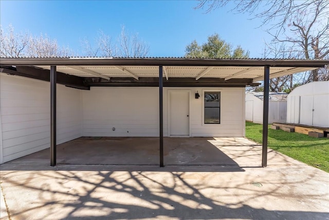 view of patio / terrace featuring an attached carport, an outdoor structure, a storage shed, and fence