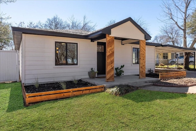 back of house featuring a garden, fence, a carport, and a yard