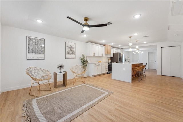 interior space featuring light wood finished floors, visible vents, stainless steel fridge with ice dispenser, a breakfast bar area, and a sink