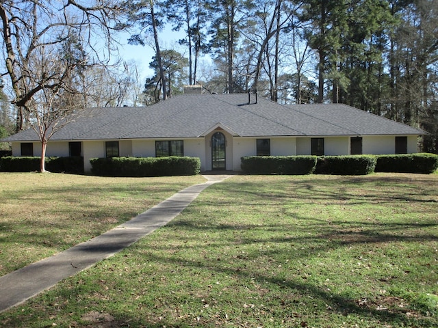 ranch-style home featuring roof with shingles and a front yard