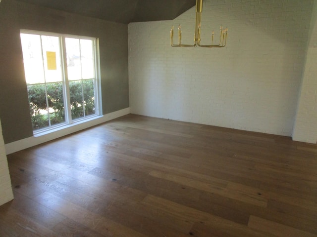 spare room featuring brick wall and wood finished floors