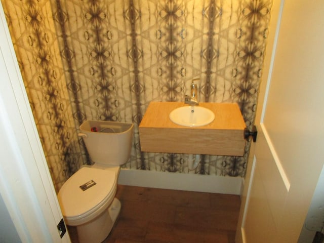 bathroom with a sink, toilet, and baseboards