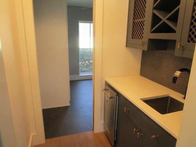 kitchen with tasteful backsplash, light countertops, light wood-style floors, a sink, and dishwasher