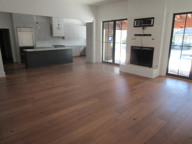 unfurnished living room with a brick fireplace and wood finished floors