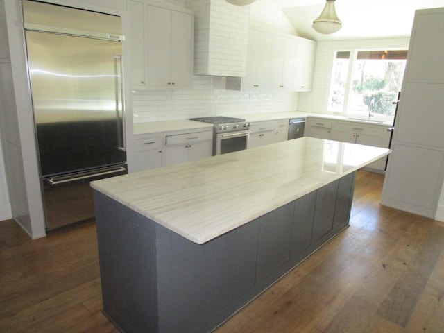 kitchen featuring wall chimney exhaust hood, dark wood-type flooring, high quality appliances, and white cabinets