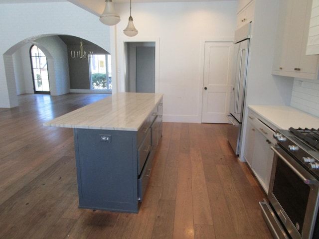 kitchen featuring high end appliances, a center island, dark wood-style flooring, and arched walkways