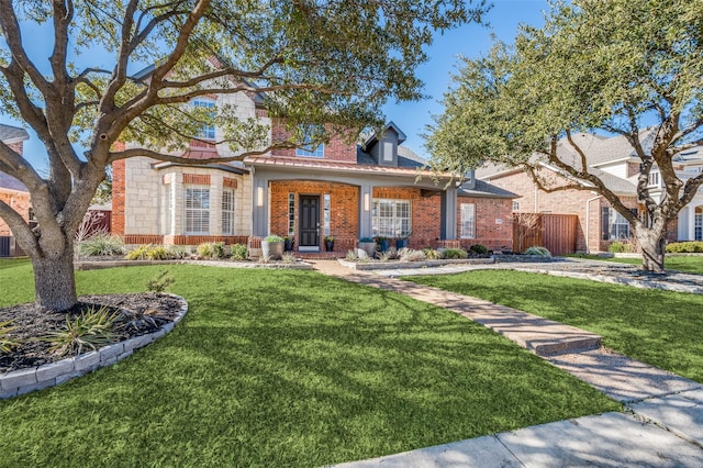 view of front of property featuring brick siding, fence, and a front yard