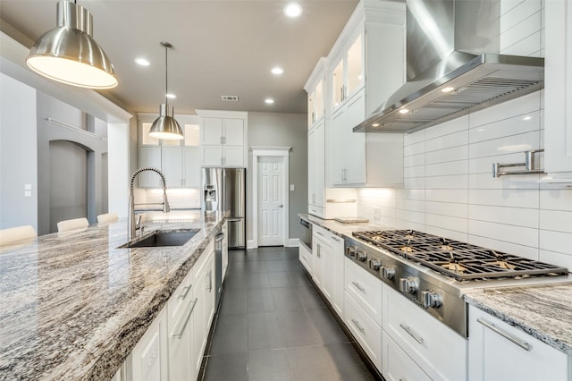 kitchen featuring arched walkways, white cabinets, wall chimney exhaust hood, stainless steel appliances, and a sink