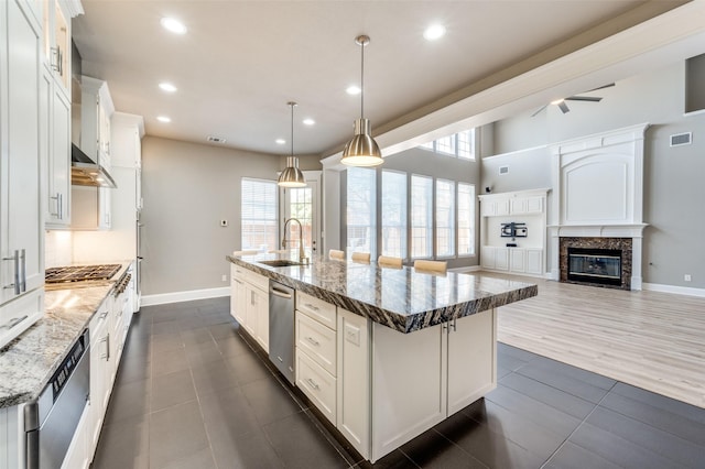 kitchen with a wealth of natural light, visible vents, stainless steel dishwasher, a sink, and an island with sink