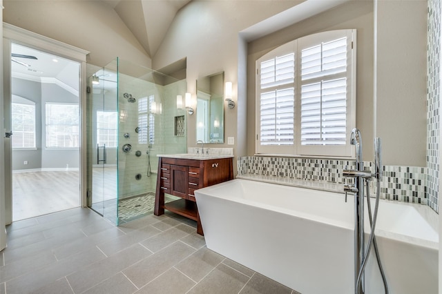 full bath featuring lofted ceiling, vanity, ornamental molding, a soaking tub, and a stall shower