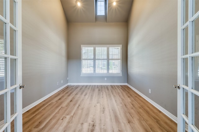 empty room featuring baseboards, wood finished floors, and french doors