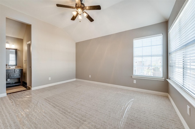 unfurnished room with a healthy amount of sunlight, vaulted ceiling, baseboards, and ceiling fan