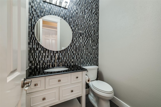 half bathroom with toilet, tasteful backsplash, baseboards, and vanity