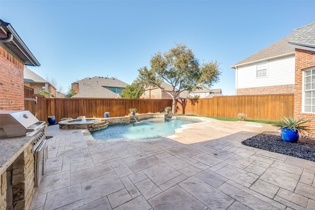 view of swimming pool with a fenced backyard, a pool with connected hot tub, exterior kitchen, and a patio