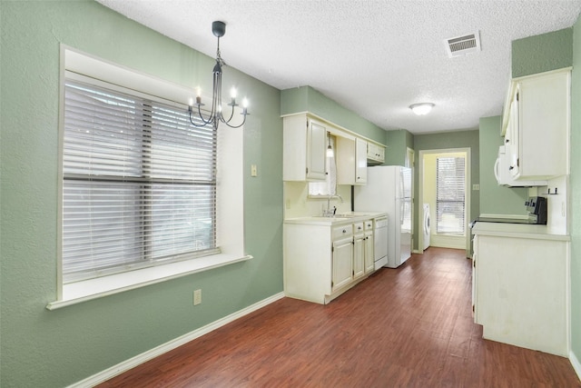 kitchen with white appliances, visible vents, dark wood-type flooring, an inviting chandelier, and light countertops