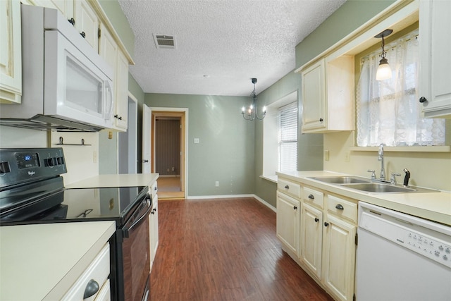 kitchen with dark wood finished floors, light countertops, visible vents, a sink, and white appliances