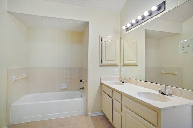 bathroom featuring a garden tub, a textured ceiling, a sink, and tile patterned floors