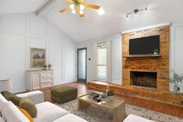 living area with vaulted ceiling with beams, a decorative wall, wood finished floors, a ceiling fan, and a brick fireplace