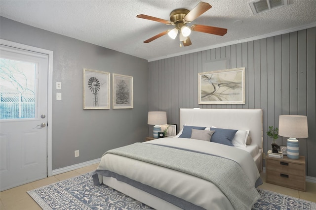 bedroom featuring ceiling fan, visible vents, a textured ceiling, and tile patterned floors