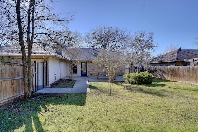 rear view of property with a yard, a patio area, and a fenced backyard