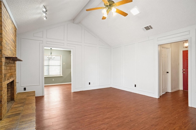 unfurnished living room featuring a brick fireplace, visible vents, a decorative wall, and wood finished floors