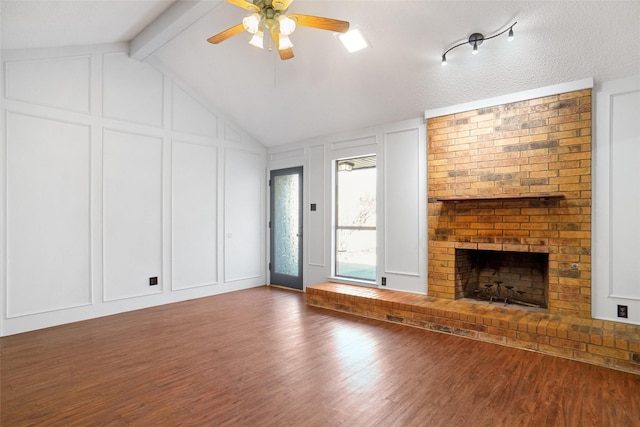 unfurnished living room featuring a fireplace, wood finished floors, and a decorative wall