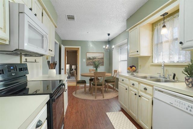 kitchen featuring white appliances, visible vents, dark wood-type flooring, light countertops, and a sink