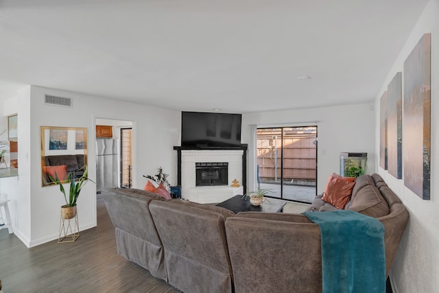 living room featuring baseboards, wood finished floors, visible vents, and a glass covered fireplace