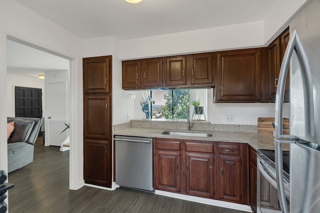 kitchen featuring a sink, light stone counters, dark wood-style floors, and stainless steel appliances