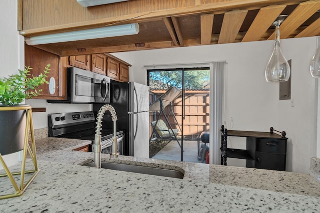 kitchen with a sink, light stone counters, brown cabinets, and stainless steel appliances