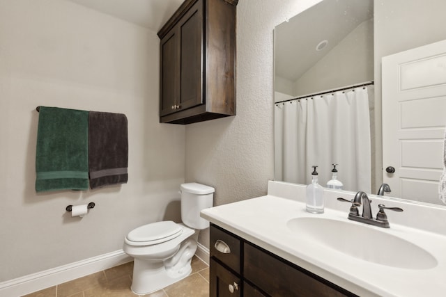 bathroom with baseboards, toilet, lofted ceiling, tile patterned floors, and vanity