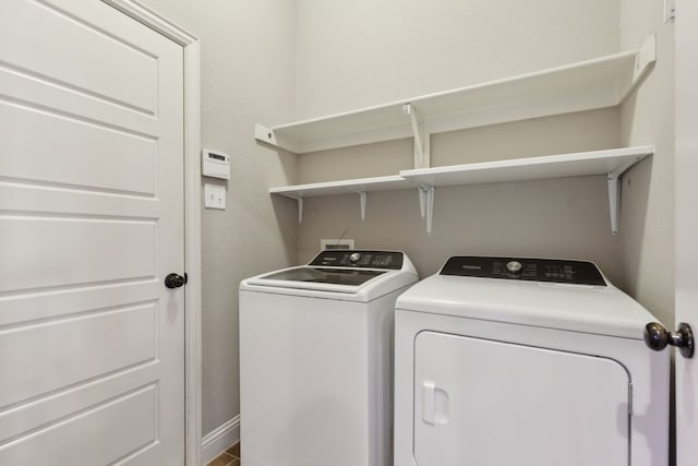 clothes washing area featuring laundry area, baseboards, and washing machine and clothes dryer