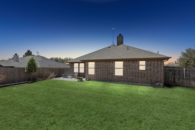 back of house with a patio, a fenced backyard, brick siding, a yard, and roof with shingles