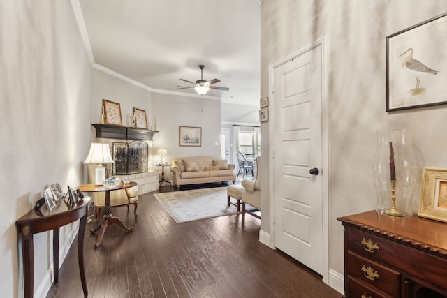 sitting room featuring a ceiling fan, dark wood-style flooring, crown molding, and baseboards