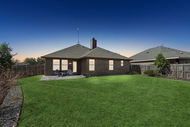 rear view of property featuring a fenced backyard, a chimney, a lawn, and a patio